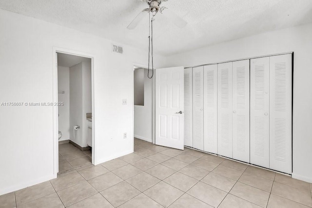 unfurnished bedroom featuring light tile patterned floors, a textured ceiling, visible vents, a ceiling fan, and a closet