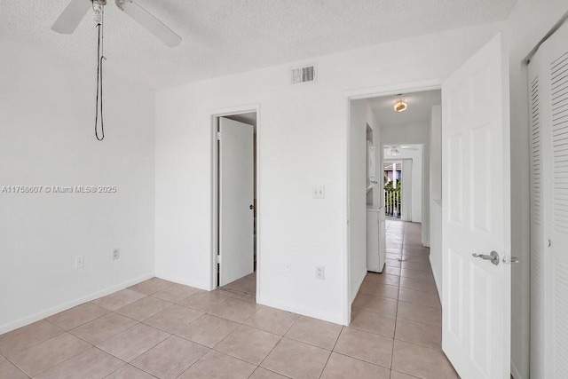 unfurnished bedroom with light tile patterned floors, a textured ceiling, visible vents, and a closet