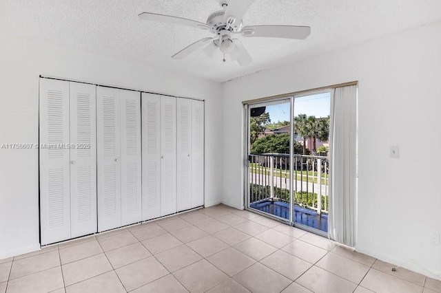 unfurnished bedroom featuring light tile patterned floors, access to outside, multiple windows, and a textured ceiling