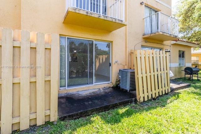 doorway to property with central air condition unit, a balcony, fence, and stucco siding