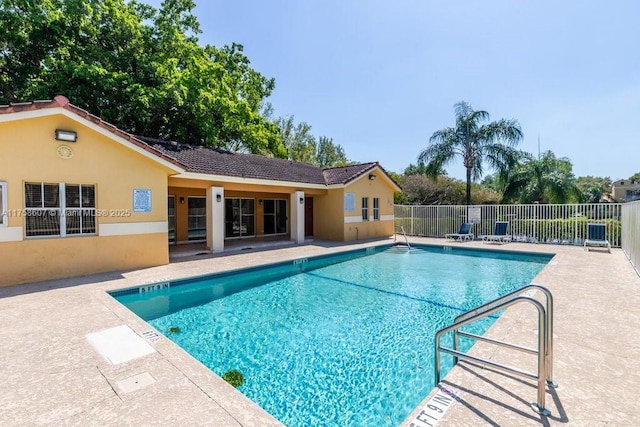 community pool with a patio area and fence