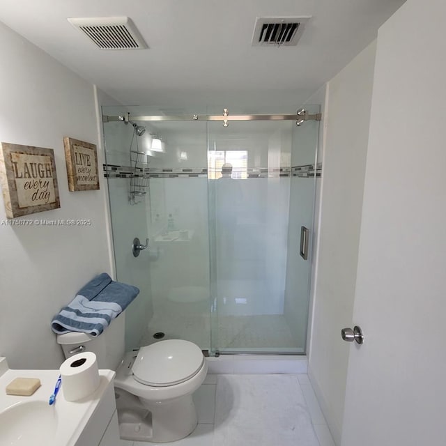 bathroom featuring toilet, a stall shower, visible vents, and a sink