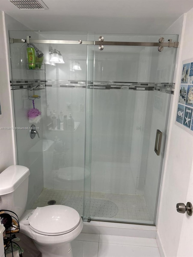 bathroom featuring toilet, a shower stall, visible vents, and tile patterned floors