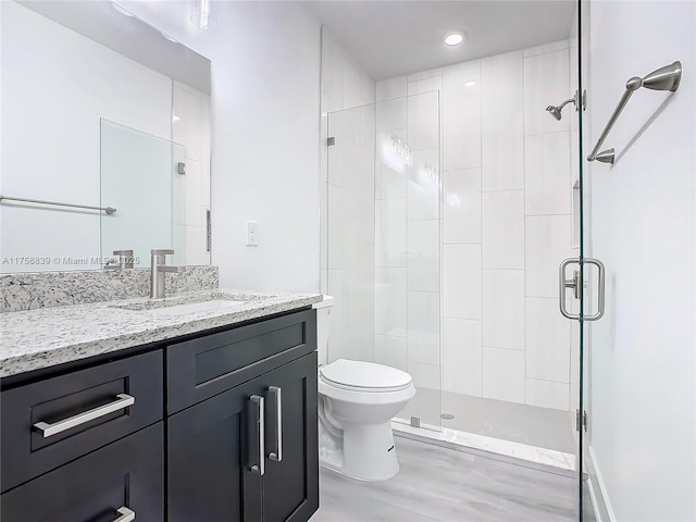 bathroom featuring recessed lighting, a stall shower, toilet, and vanity