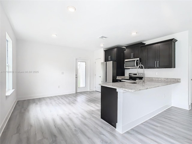 kitchen featuring visible vents, baseboards, light stone countertops, light wood-type flooring, and stainless steel appliances