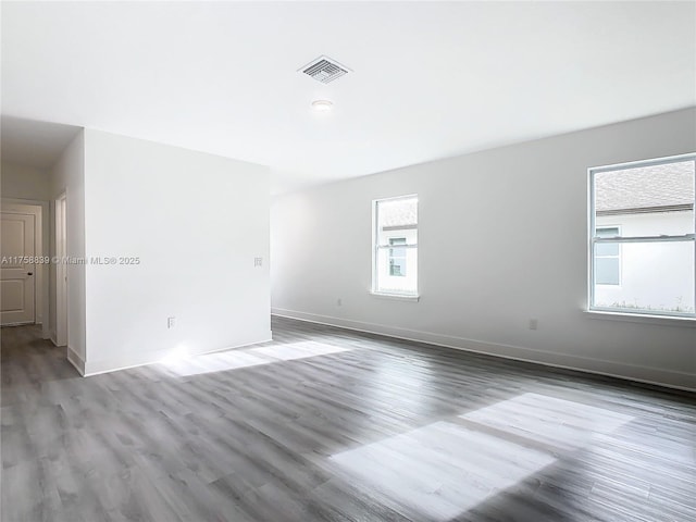 unfurnished room featuring visible vents, baseboards, and wood finished floors