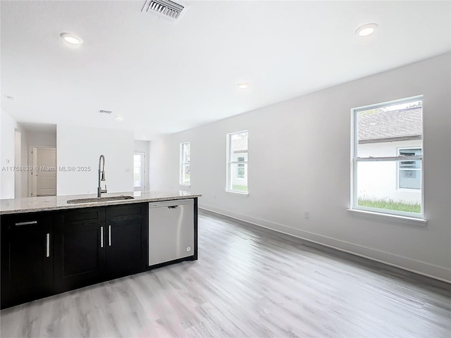 kitchen with stainless steel dishwasher, light stone countertops, visible vents, and a sink