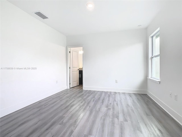 unfurnished room featuring wood finished floors, baseboards, and visible vents