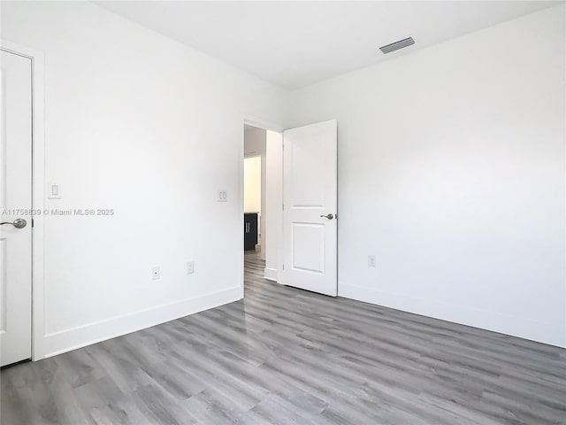 unfurnished room featuring wood finished floors, visible vents, and baseboards