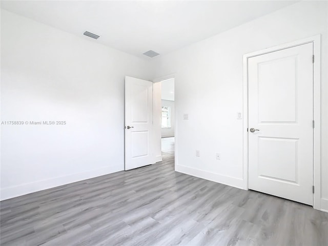 unfurnished bedroom featuring light wood finished floors, visible vents, and baseboards