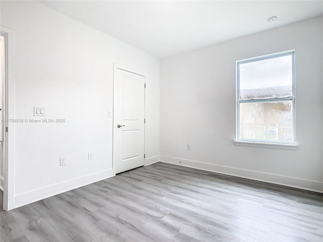 empty room with baseboards and wood finished floors