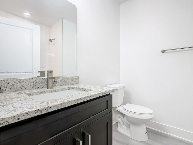 bathroom featuring a shower, baseboards, toilet, and vanity