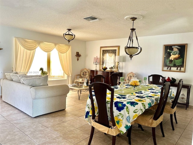 dining area with a textured ceiling, light tile patterned flooring, and visible vents