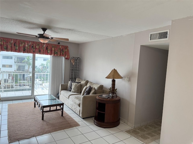 living area with a textured ceiling, ceiling fan, light tile patterned flooring, and visible vents