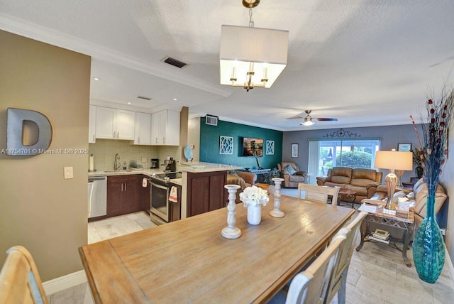 dining area featuring visible vents, crown molding, light wood-style flooring, and a textured ceiling