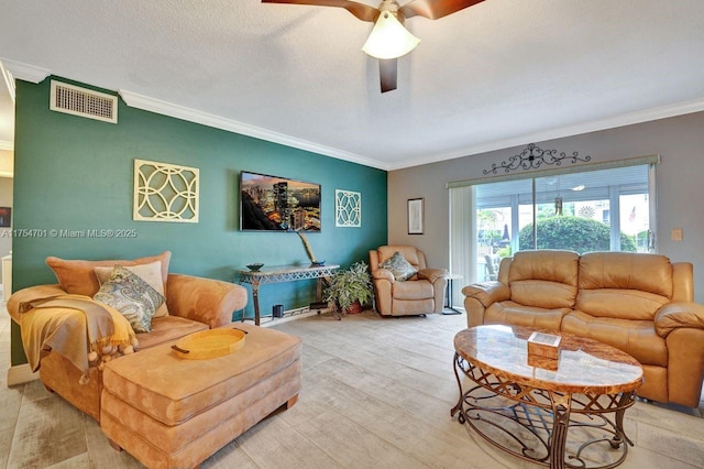 living room featuring crown molding, visible vents, a ceiling fan, a textured ceiling, and light wood-type flooring