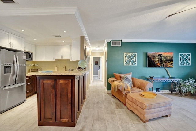 kitchen featuring appliances with stainless steel finishes, white cabinets, visible vents, and light wood-style flooring