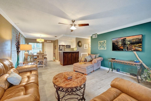 living room featuring a textured ceiling, visible vents, baseboards, a ceiling fan, and ornamental molding