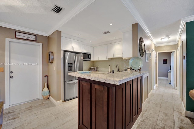 kitchen with tasteful backsplash, appliances with stainless steel finishes, visible vents, and white cabinets