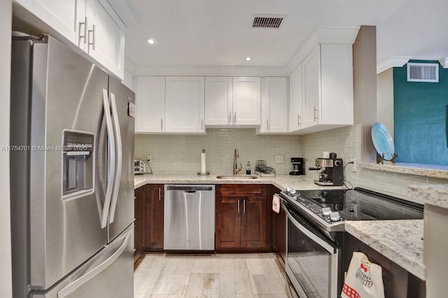 kitchen featuring light stone counters, tasteful backsplash, visible vents, appliances with stainless steel finishes, and a sink