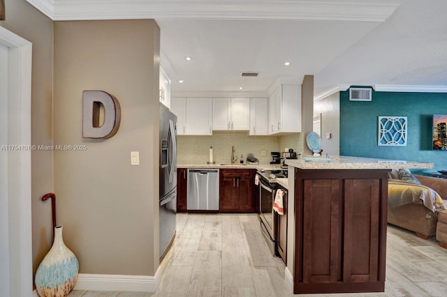 kitchen featuring visible vents, appliances with stainless steel finishes, open floor plan, white cabinets, and a peninsula