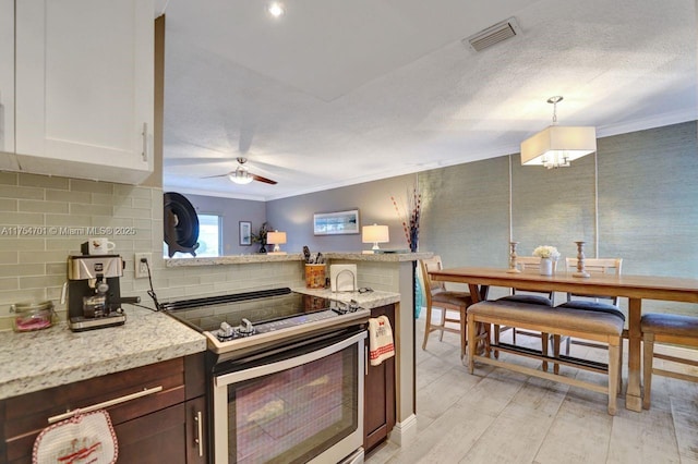 kitchen featuring a peninsula, visible vents, ornamental molding, stainless steel electric range, and decorative backsplash