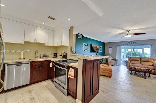 kitchen with visible vents, appliances with stainless steel finishes, open floor plan, a sink, and a peninsula