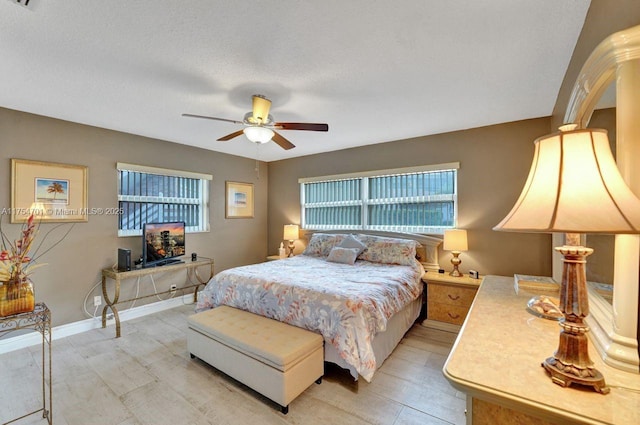 bedroom with a ceiling fan, baseboards, a textured ceiling, and light wood finished floors