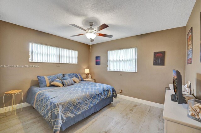 bedroom featuring a textured ceiling, light wood finished floors, a ceiling fan, and baseboards