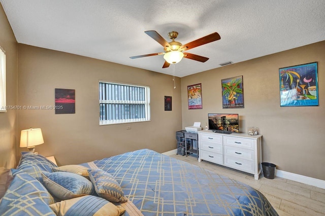 bedroom with visible vents, a textured ceiling, and baseboards