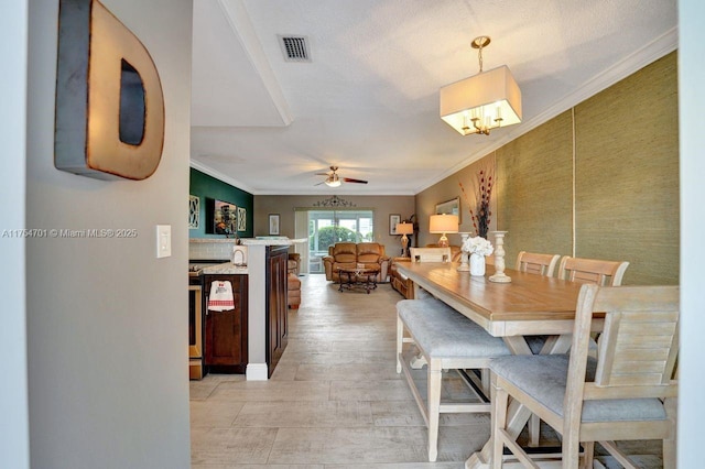 dining area with ornamental molding, visible vents, ceiling fan, and light wood finished floors