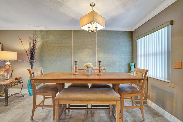 dining area with baseboards, a textured ceiling, light wood-type flooring, and crown molding