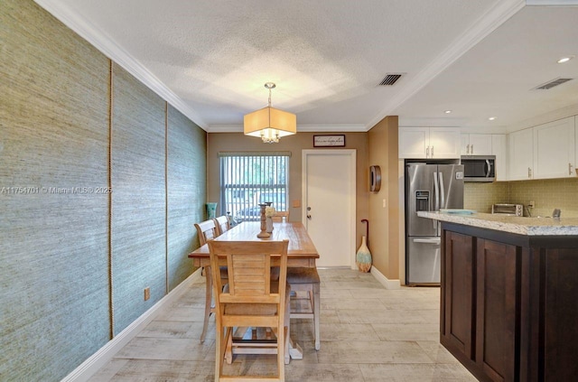 dining room featuring ornamental molding, visible vents, a textured ceiling, and wallpapered walls