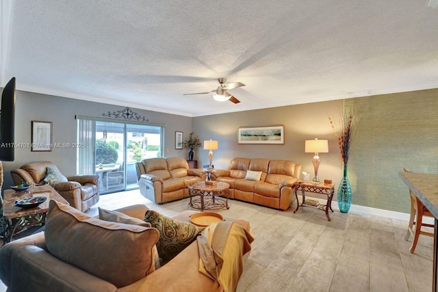 living room featuring a textured ceiling, a ceiling fan, baseboards, ornamental molding, and light wood-type flooring