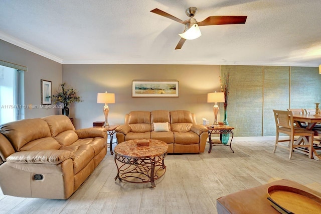 living room featuring a textured ceiling, light wood finished floors, ornamental molding, and a ceiling fan