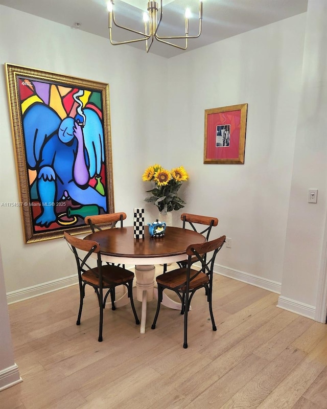 dining space with a chandelier, light wood-style flooring, and baseboards