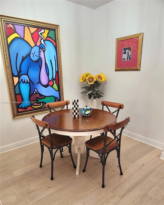 dining space with light wood-type flooring and baseboards