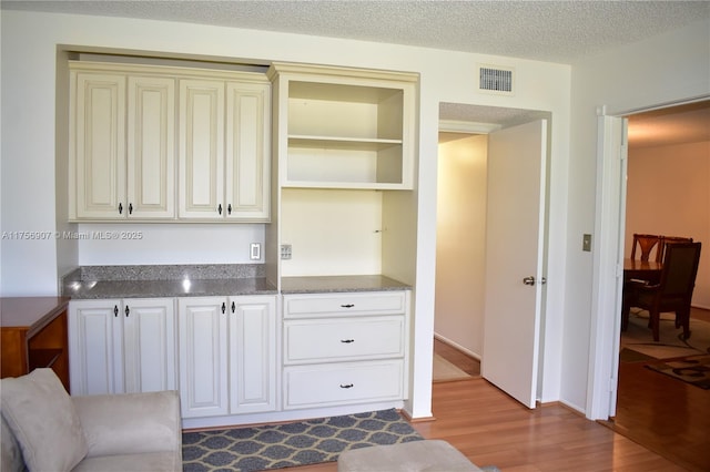 3970 Oaks Clubhouse Dr Unit 307, Pompano Beach, FL 33069 - interior space featuring wood finished floors, open shelves, cream cabinets, and a textured ceiling