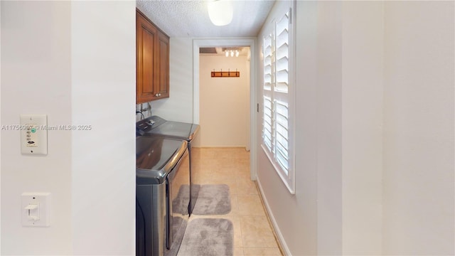 3970 Oaks Clubhouse Dr Unit 307, Pompano Beach, FL 33069 - washroom featuring separate washer and dryer, cabinet space, light tile patterned floors, a textured ceiling, and baseboards