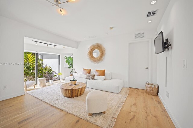 living area with baseboards, wood finished floors, visible vents, and recessed lighting