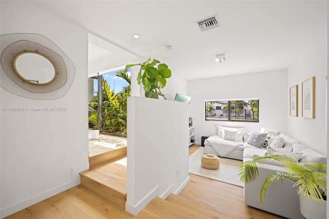 living room featuring baseboards, visible vents, and wood finished floors