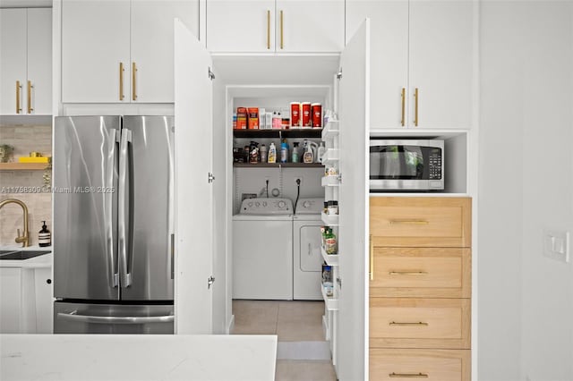 storage area featuring separate washer and dryer and a sink