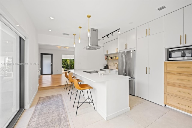 kitchen with light countertops, appliances with stainless steel finishes, a sink, a kitchen breakfast bar, and extractor fan