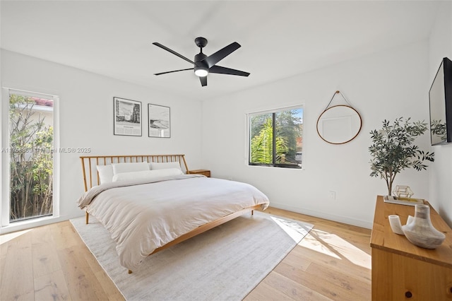 bedroom with light wood-style floors, baseboards, and a ceiling fan