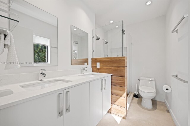 bathroom with double vanity, a stall shower, a sink, and toilet