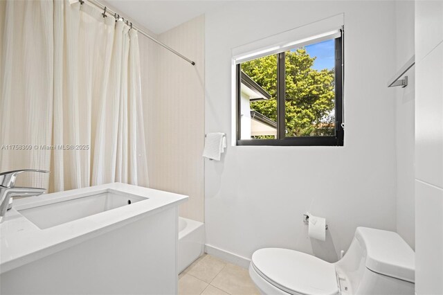 full bathroom with baseboards, toilet, tile patterned floors, shower / bathtub combination with curtain, and a sink