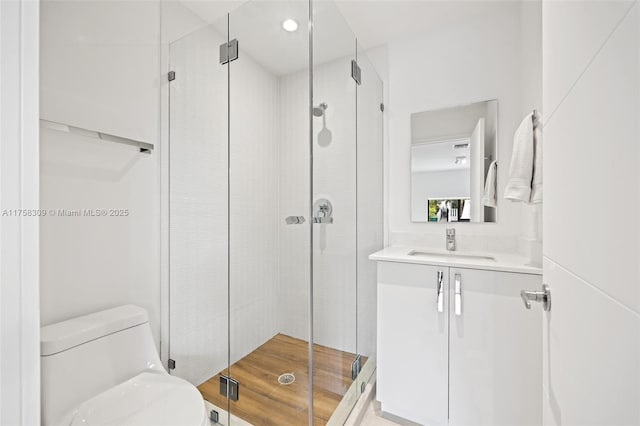 bathroom with wood finished floors, a stall shower, vanity, and toilet