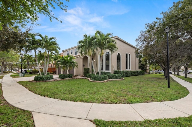 mediterranean / spanish house with a front lawn and stucco siding