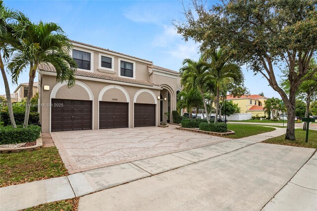 mediterranean / spanish-style home with a tile roof, decorative driveway, and stucco siding