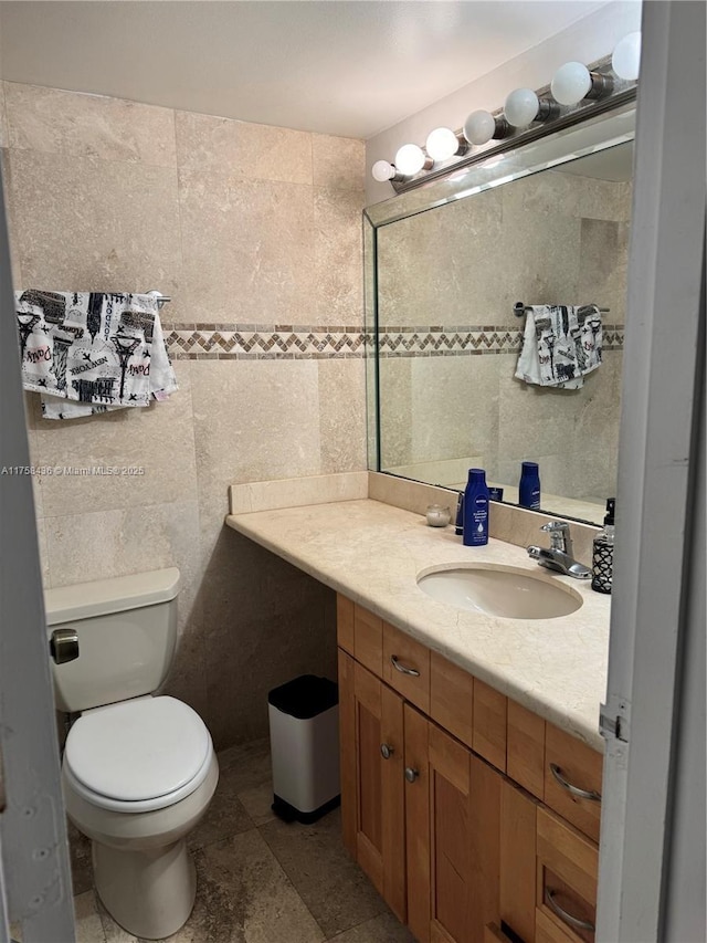 bathroom featuring toilet, tile walls, and vanity